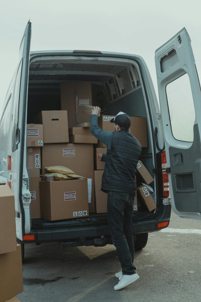 A courier organizing boxes in a delivery van for shipment on a cloudy day.